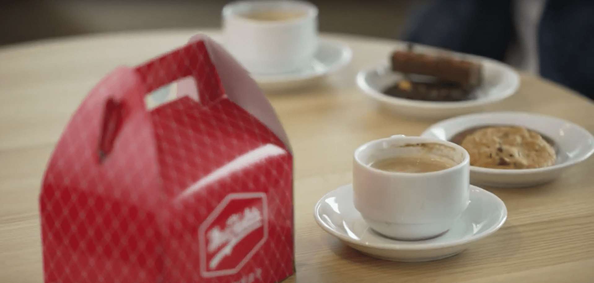 A cup of coffee and pieces of cookies on the table.